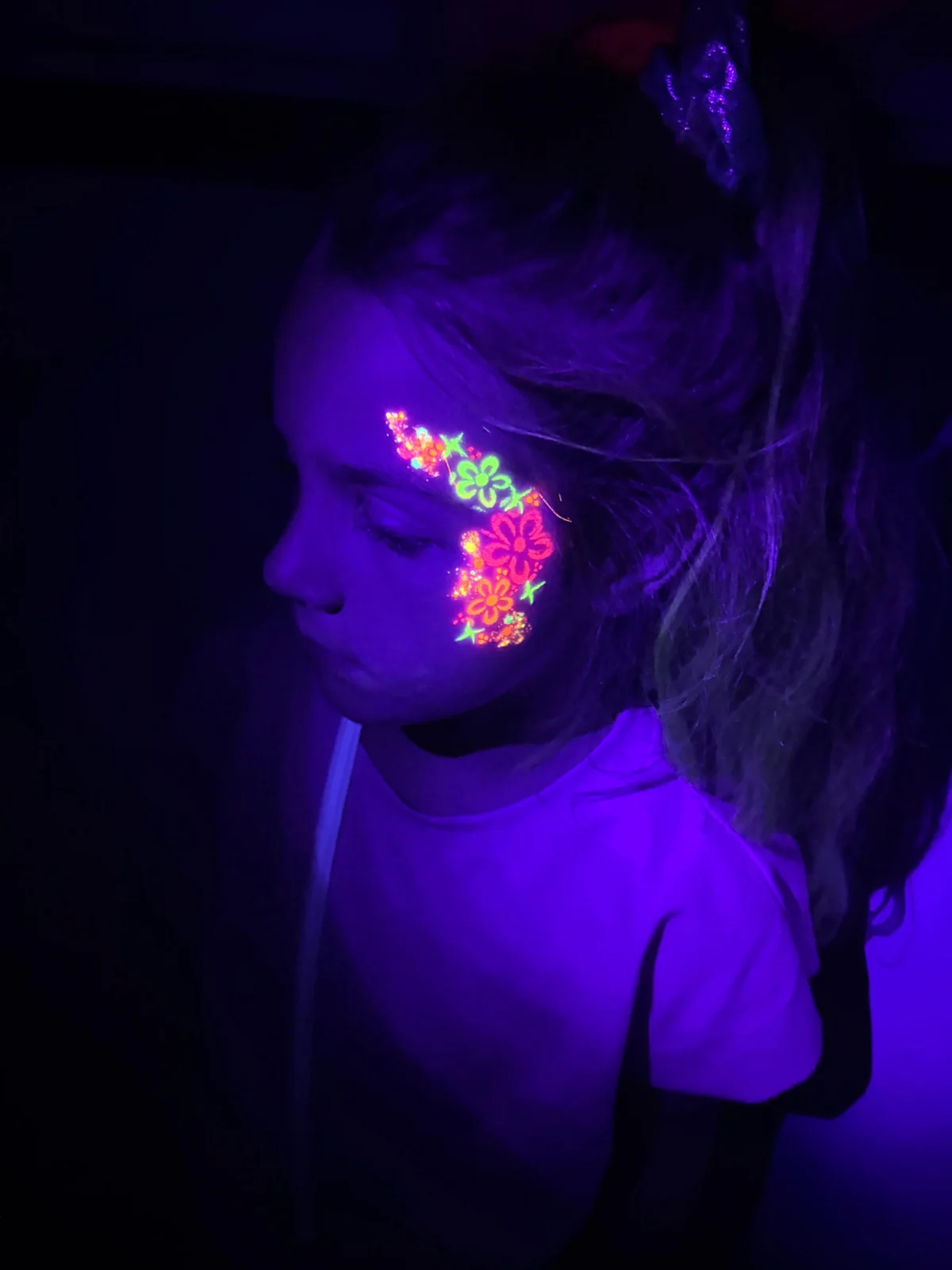 Gezichtsschmink met lichtgevende bloemen onder ultraviolet licht